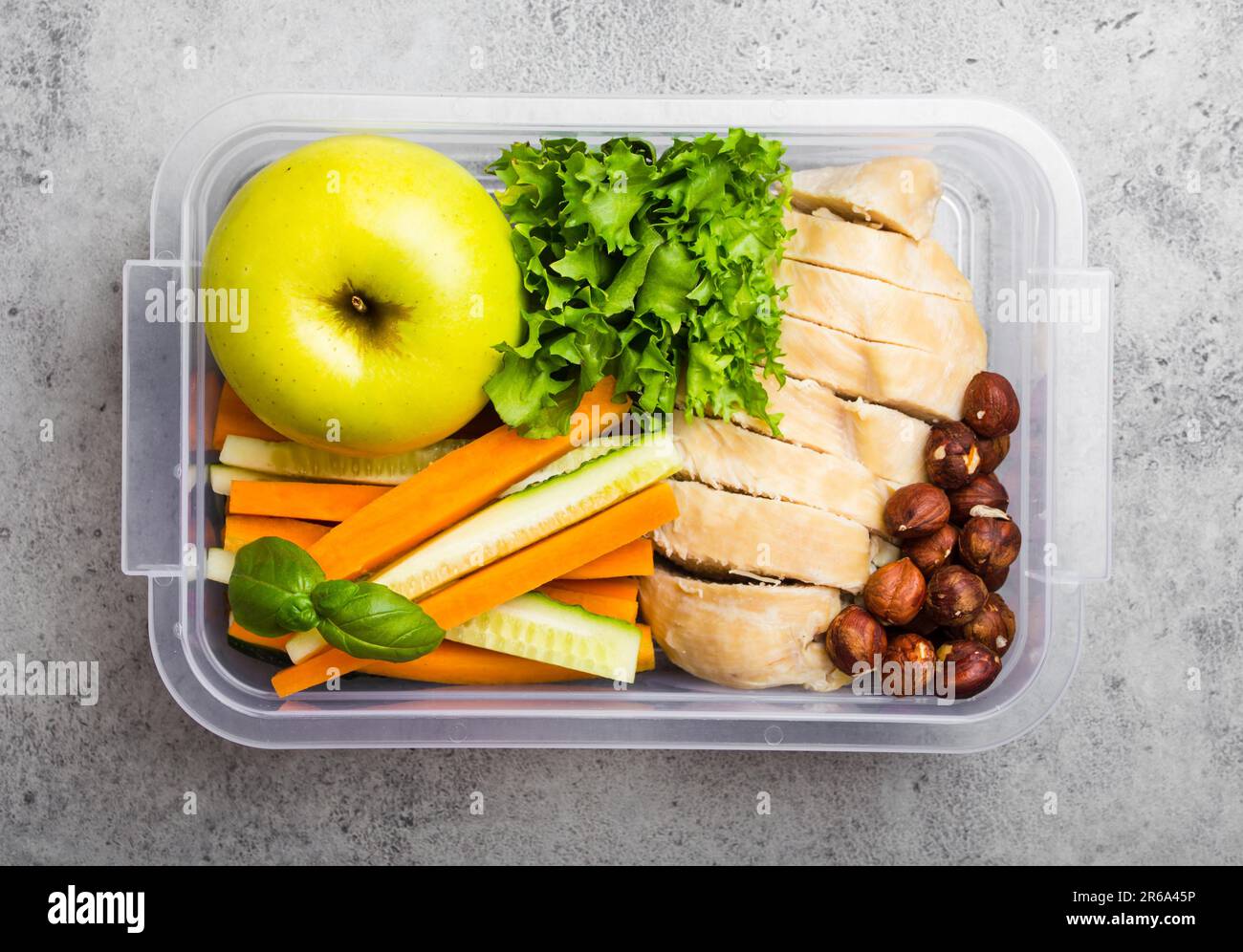 Gesundes Essen Lunchbox für Büro oder Schule: Hühnerfilet, Karotten, Gurkenstangen, Salat, Apfel. Zubereitung und Verpackung des Essens für den Support Stockfoto