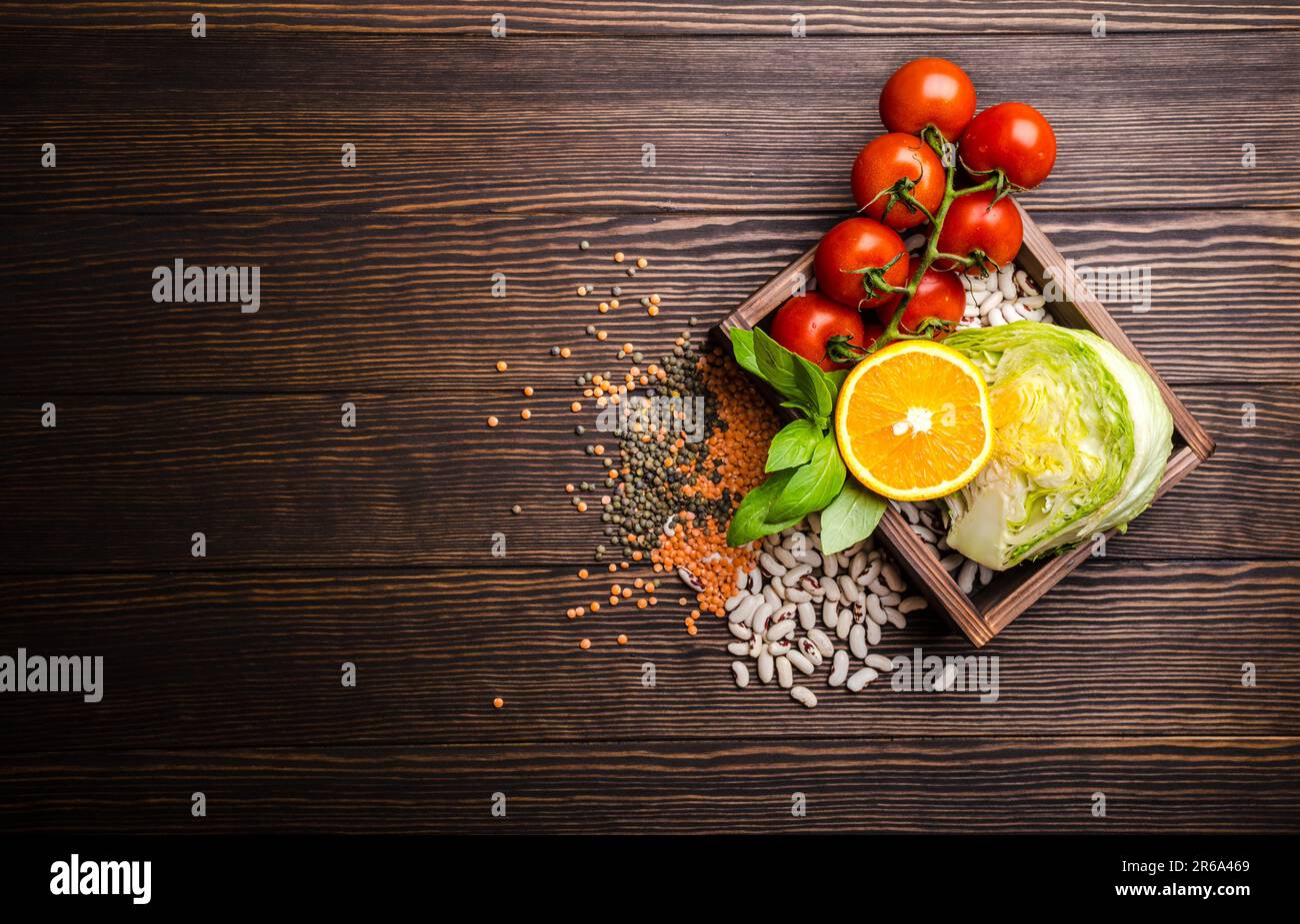 Draufsicht auf gesunde Ernährung Lebensmittelzutaten in Holzbox: Gemüse, Bohnen, Obst, Kräuter mit Platz für Text, rustikaler Holzhintergrund. Essen Stockfoto
