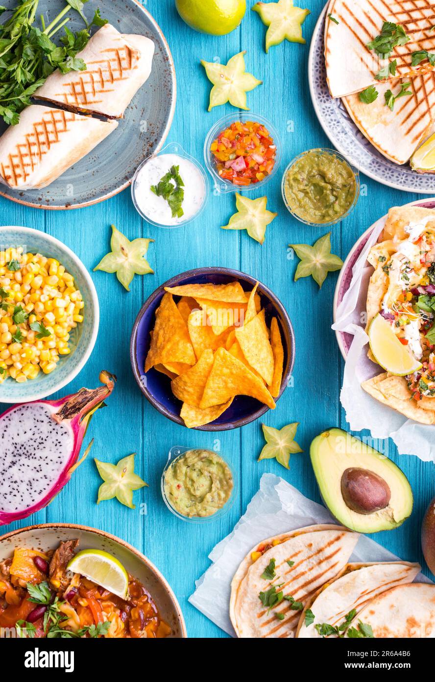 Gemischter Mix aus traditioneller mexikanischer Küche. Tisch mit verschiedenen mexikanischen Gerichten. Käsenachos, Tacos, Guacamole, Quesadilla, Burrito, Fajitas, Tortilla Stockfoto