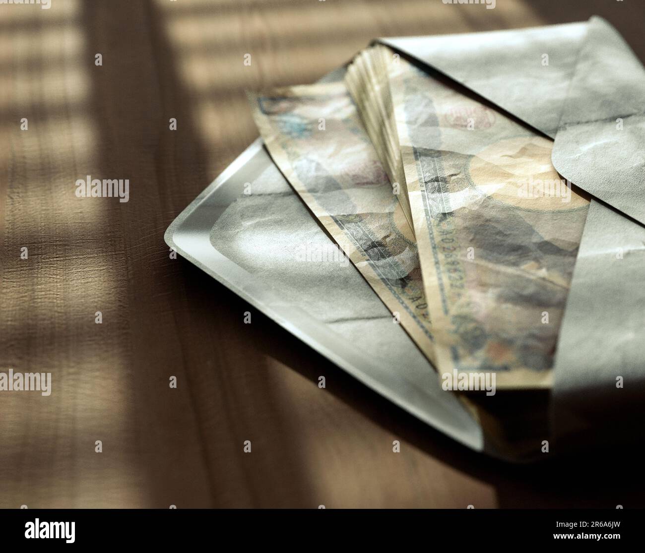 Ein Stapel Yen-Banknoten in einem Umschlag auf einer Holzfläche unter stimmungsvoller Beleuchtung - 3D-Darstellung Stockfoto