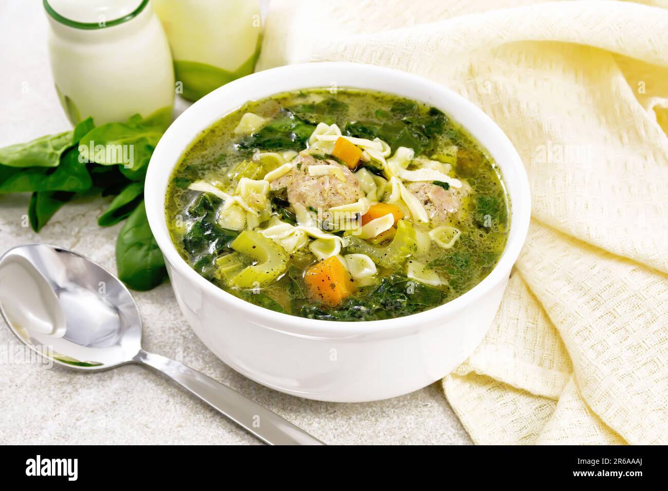 Italienische Suppe Ministra Maritata mit Fleischbällchen, Spinat, Karotten, Petiolsellerie und feiner Pasta in einer Schüssel, Serviette und Löffel auf Granithintergrund Stockfoto