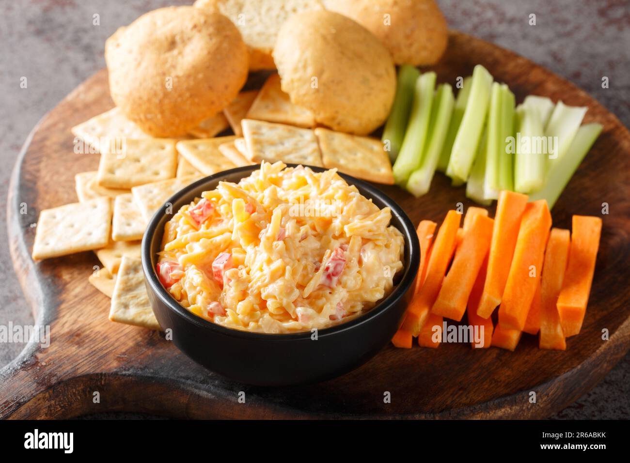 Pimento-Käse mit Sellerie, Karottenstäbchen und Crackern auf dem Holzbrett auf dem Tisch. Horizontal Stockfoto