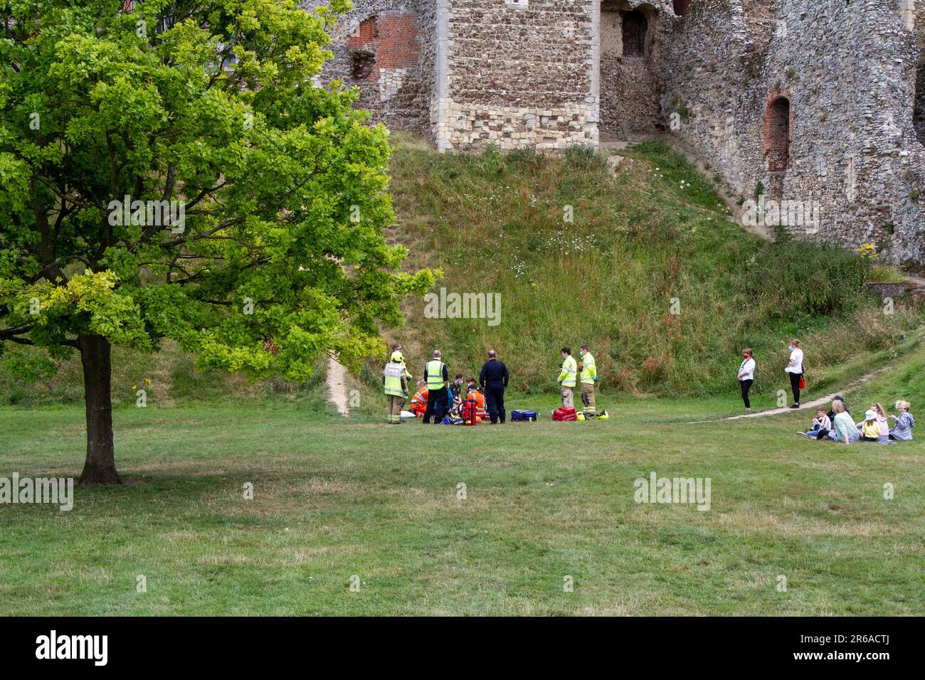 In der Kulisse des historischen Framlingham Castle gehen die Einsatzkräfte an einen Unfall am Fuße eines steilen Abhangs Stockfoto