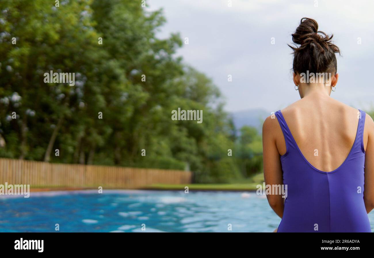 Eine schlanke, nicht wiedererkennbare Frau mit Magersucht oder Bulimie, die in den Sommerferien im Pool sitzt. Ein psychisches Problem Stockfoto