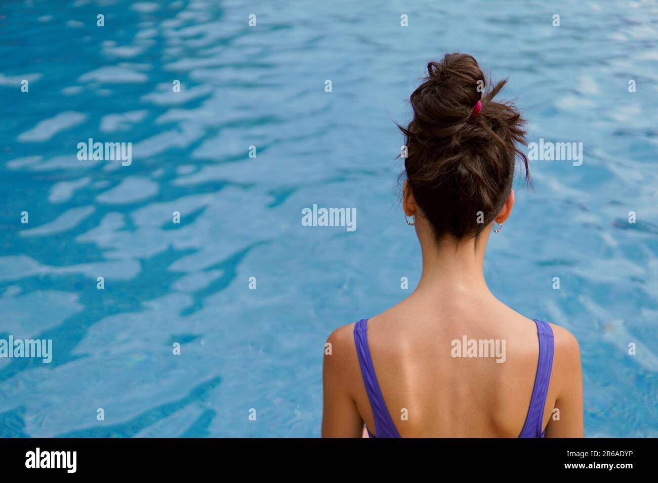 Eine schlanke Frau, die in den Sommerferien in einem Swimmingpool sitzt Stockfoto