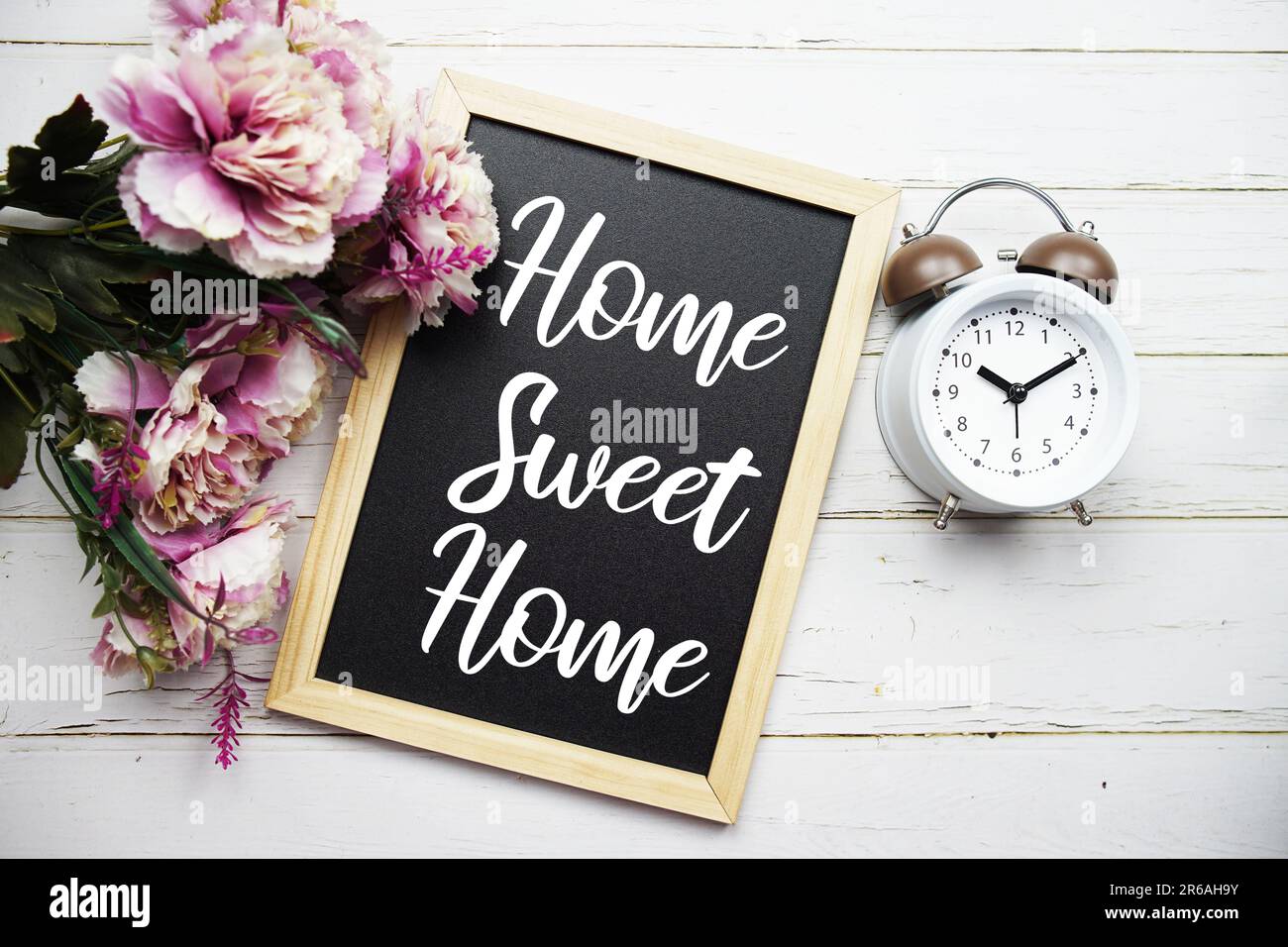 Home Sweet Home Textnachricht mit Weckruf und Blumendekoration auf Holzhintergrund Stockfoto