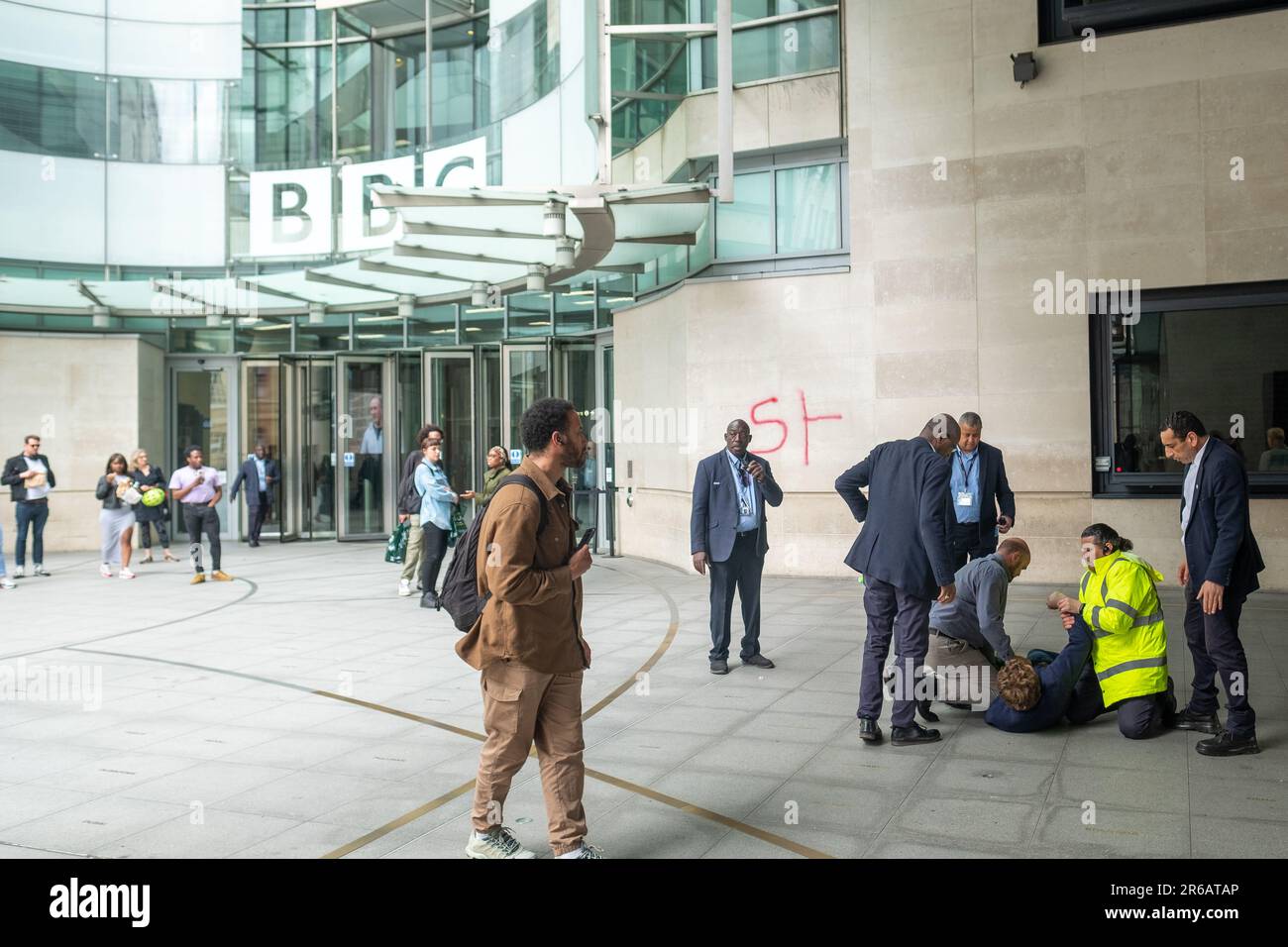London - 23. Mai 2023: Ein Anti-BBC-Protestteilnehmer versucht, etwas auf das BBC Broadcasting House zu sprühen, und wird von der Sicherheit angegriffen. Stockfoto