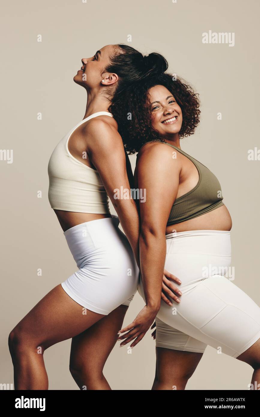 Verschiedene Fitnessmodelle in Fitnesskleidung für die Kamera im Studio. Diese beiden Sportlerinnen zeigen im Rücken ihren kräftigen bodi Stockfoto