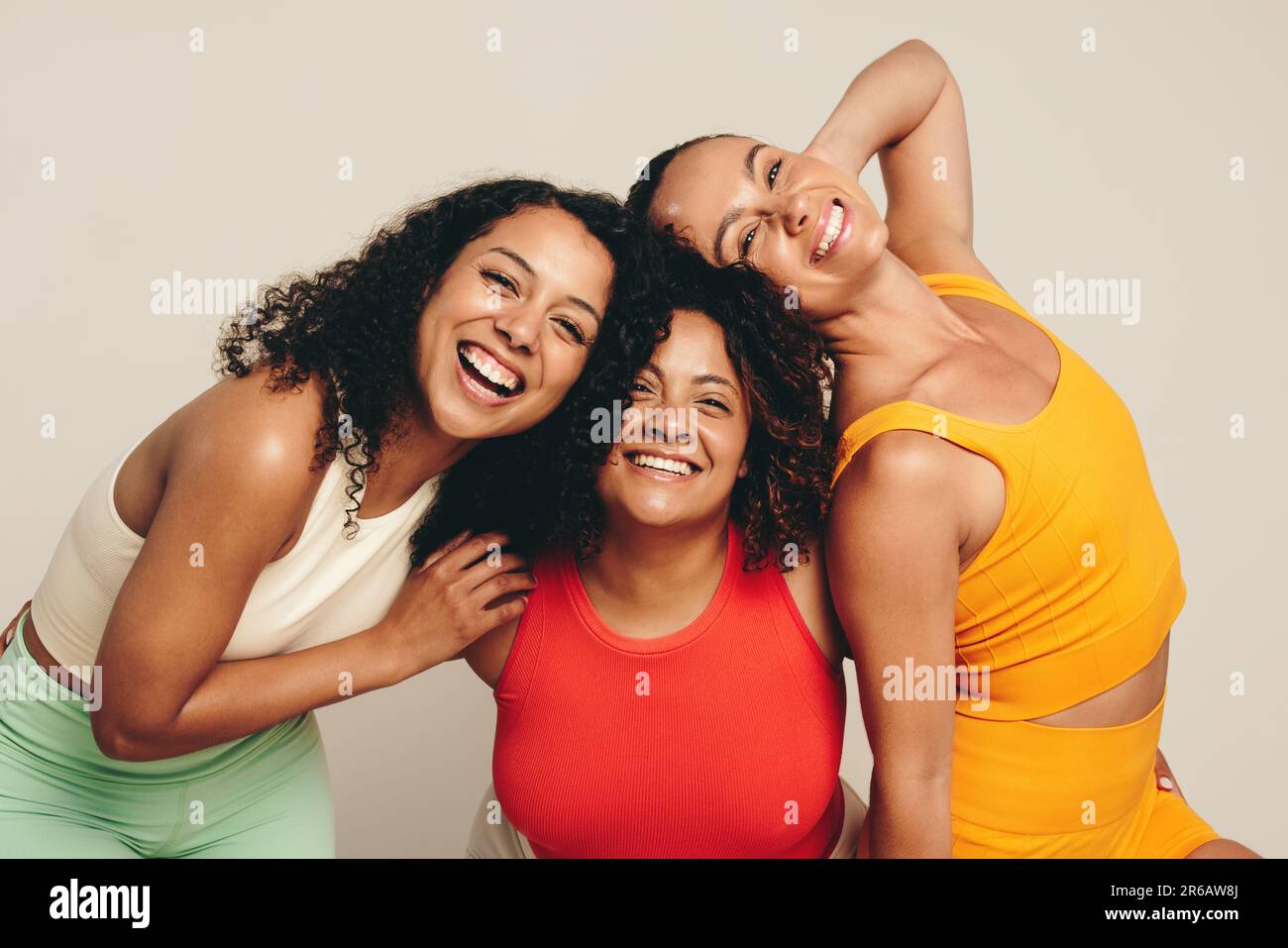 Glückliche Freundinnen lächeln in die Kamera und feiern einen gesunden Lebensstil aus Sport, Bewegung und Fitness. Gruppe junger Sportlerinnen, die zusammenstehen Stockfoto