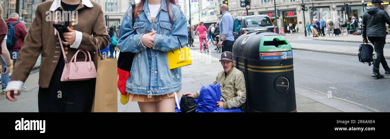 London - März 2023: Ein Obdachloser sitzt versunken, während die Käufer an der Oxford Street vorbeigehen Stockfoto
