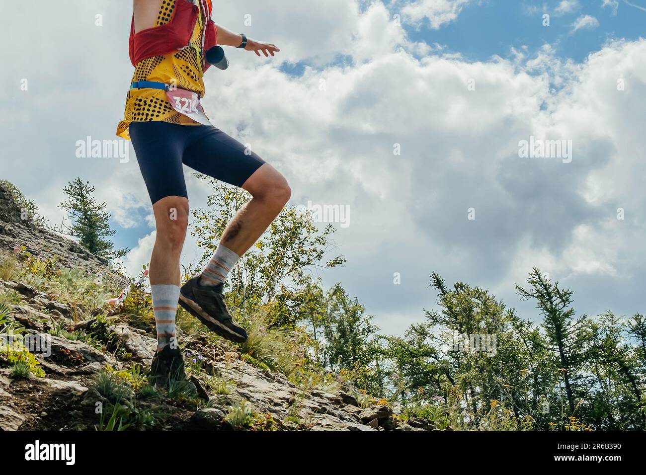 Männlicher Läufer balanciert auf dem steilen Berghang, Sommer Trail Marathon-Rennen Stockfoto