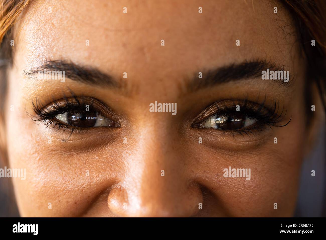 Nahaufnahmen einer selbstbewussten, birassischen jungen Frau mit schwarzen Augen, die im Fitnessclub auf die Kamera schaut Stockfoto
