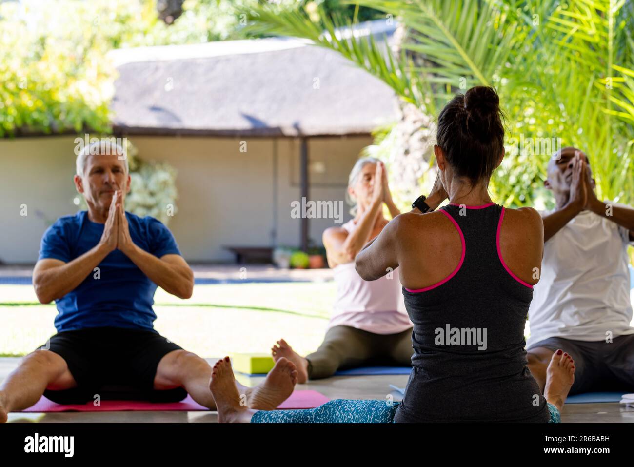Fokussierte, vielfältige Senioren, die im Pilates-Kurs mit weiblicher Trainerin trainieren Stockfoto