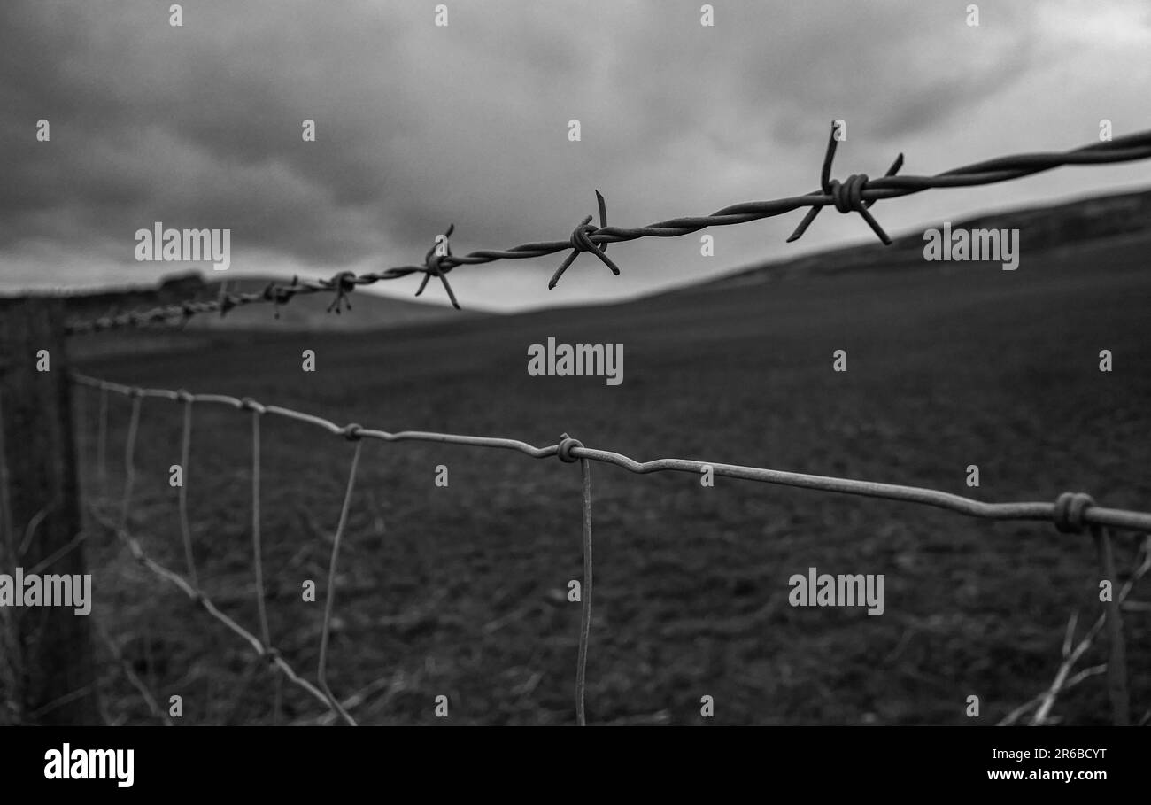 Schwarzweißfoto von Hügeln in schottland. Stacheldraht ist abgebildet nützlich für die Vermittlung von Einsamkeit, Einsamkeit, Laufen und alles, was psychische Gesundheit. Stockfoto
