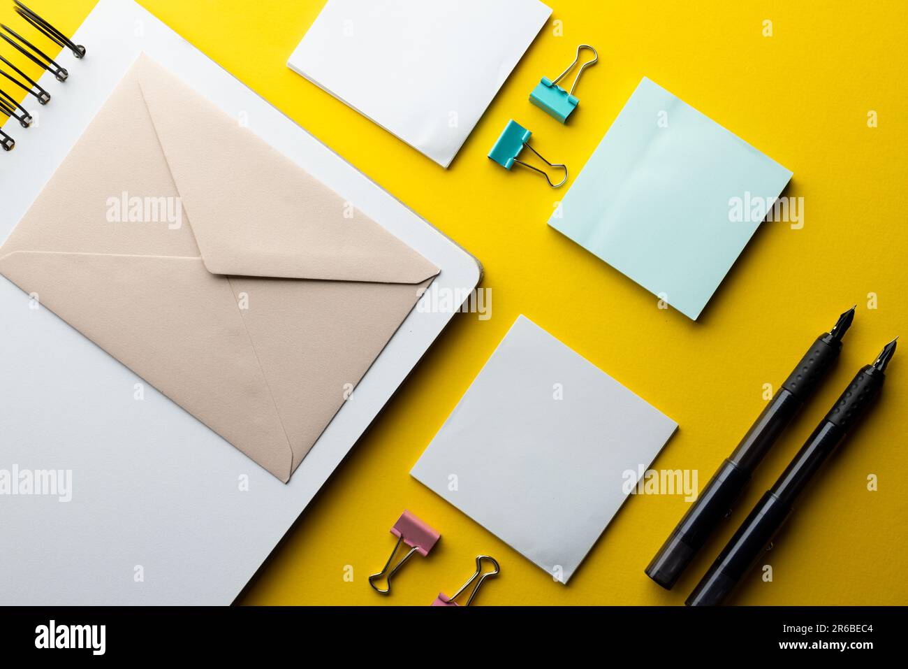 Flache Lage aus schwarzen Stiften, Umschlag und weißem Papier mit Kopierbereich auf gelbem Hintergrund. Schulmaterial, Schreiben, Malen, Zeichnen, Lernen, Schule Stockfoto