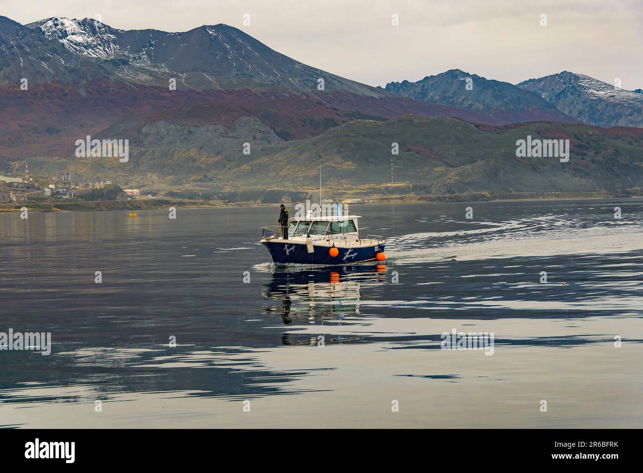 USHUAIA, ARGENTINIEN - APRIL 15 2022: Kleines Boot überquert den Beagle-Kanal mit Bergen im Hintergrund, ushuaia, tierra del fuego, argentinien Stockfoto