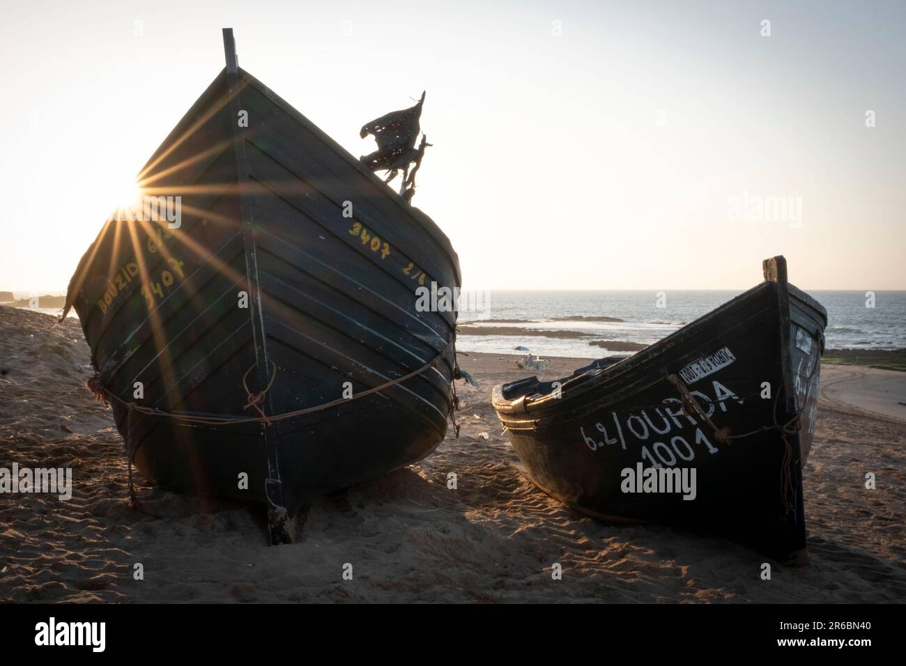 Fischerboote am Sandstrand von Oualidia in Marokko im warmen orangefarbenen Nachmittagslicht Stockfoto