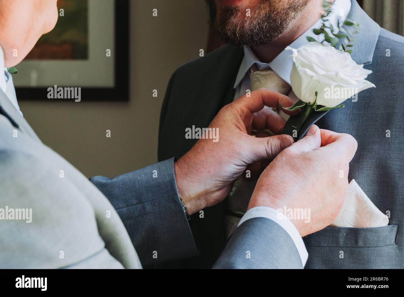 Dad hilft dem Sohn am Hochzeitstag mit dem Knopfloch Stockfoto