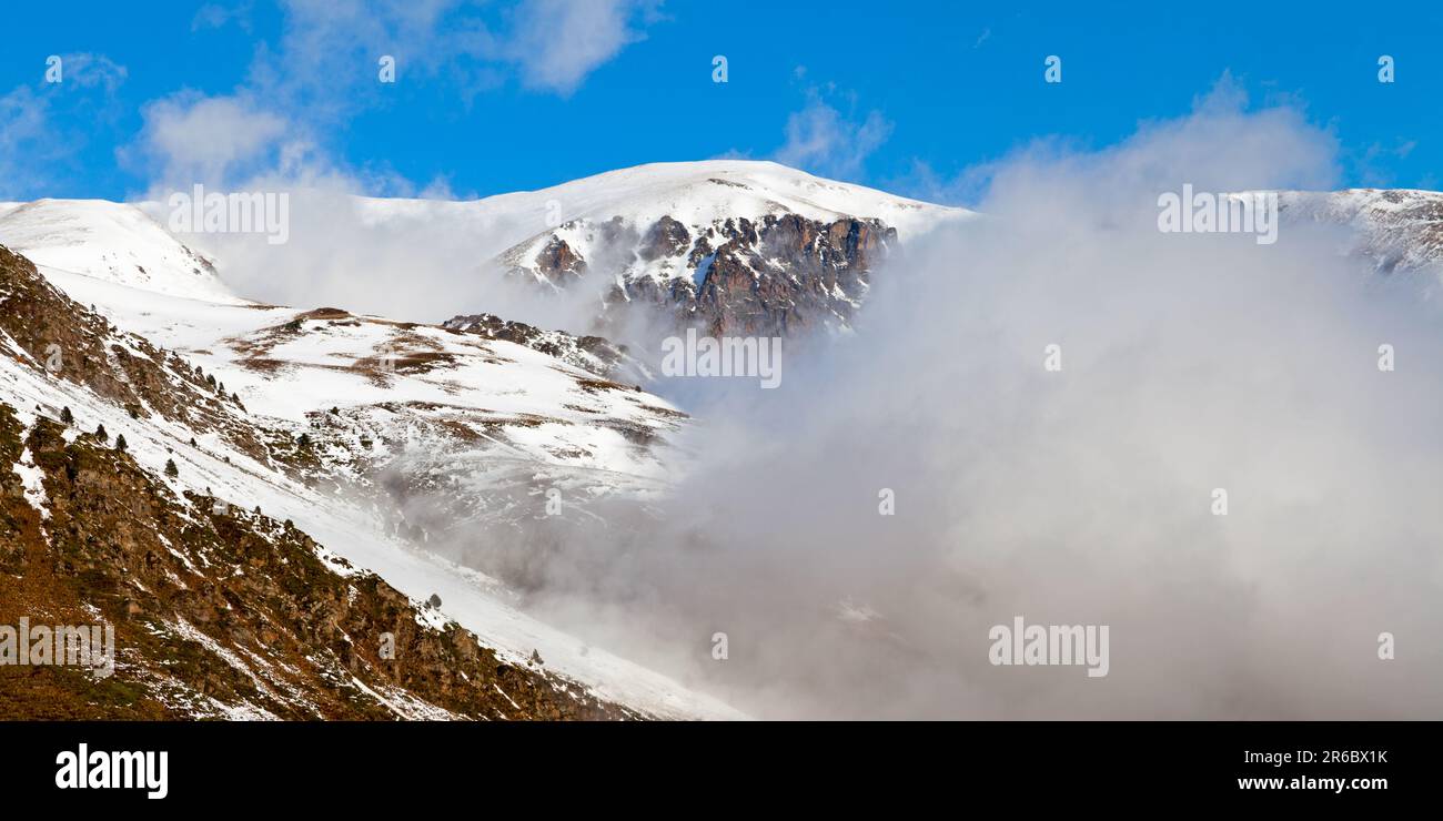Panoramablick auf die schneebedeckten Berge in Pas de la Casa (Andorra), bedeckt von Wolken. Stockfoto
