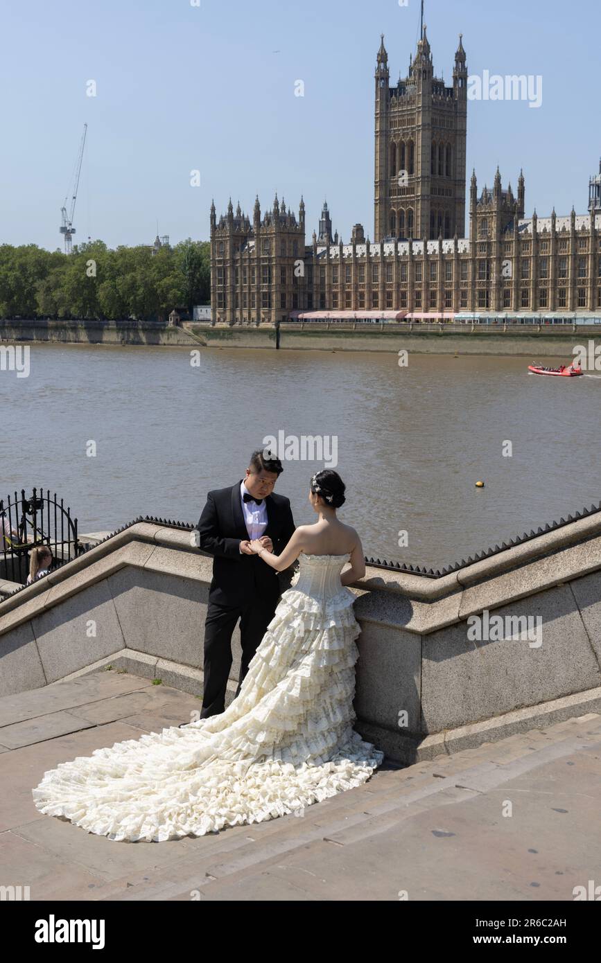 Chinesisches frisch verheiratetes Paar, das ihr Hochzeitsfoto gegenüber dem Houses of Parliament, Westminster, London, England, Großbritannien aufnehmen lässt Stockfoto