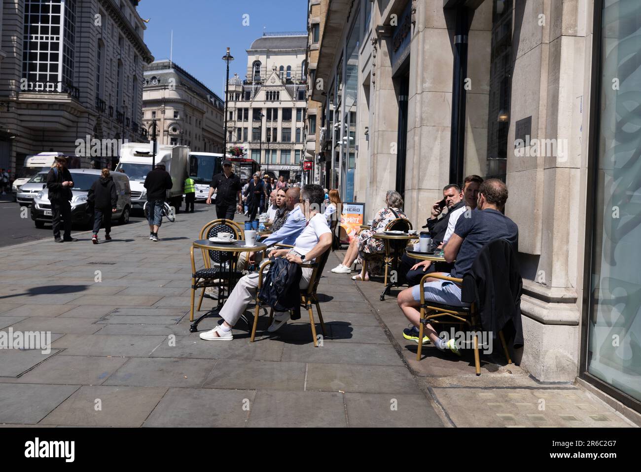Menschen sitzen an einem heißen Sommertag während einer Mini-Hitzewelle im Juni 2023 auf Haymarket, West End of London, England, UK Stockfoto