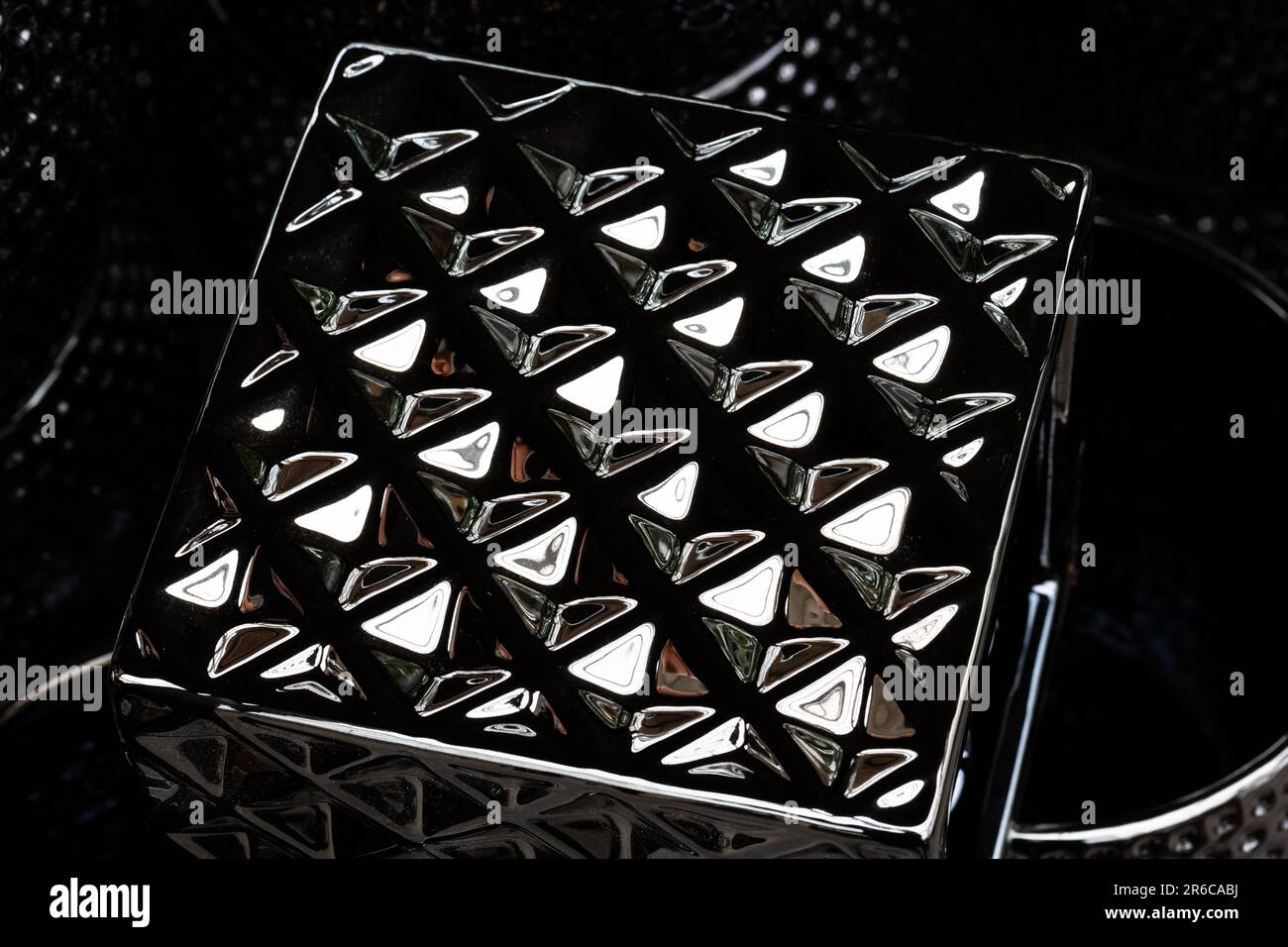 Grafische Elemente werden auf einem metallischen Quader reflektiert. Stockfoto