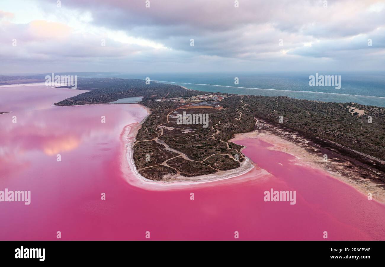 Pink Lake in Port Gregory in Westaustralien, farbenfrohes Wasser mit Bakterien und Algen, wunderschöner Kontrast zwischen dem blauen Ozean und dem rosa Wasser, Wolken Stockfoto