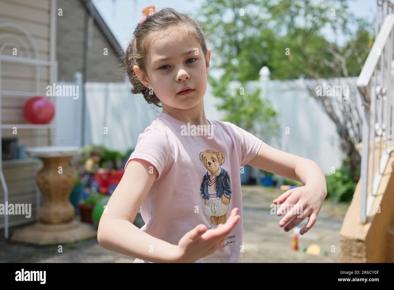 Süßes junges Mädchen, das an einem sonnigen Tag im Garten spielt Stockfoto