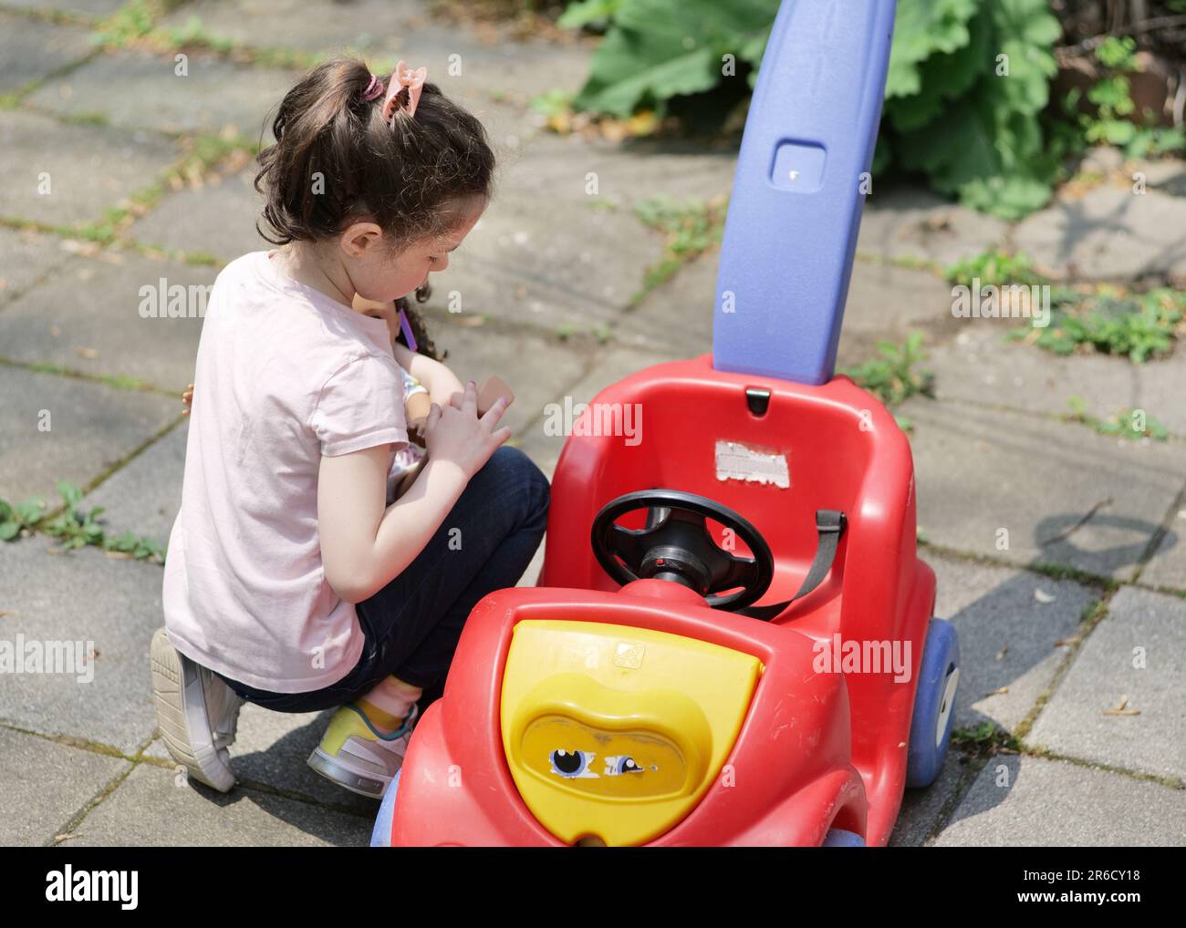Süßes junges Mädchen, das an einem sonnigen Tag im Garten spielt Stockfoto
