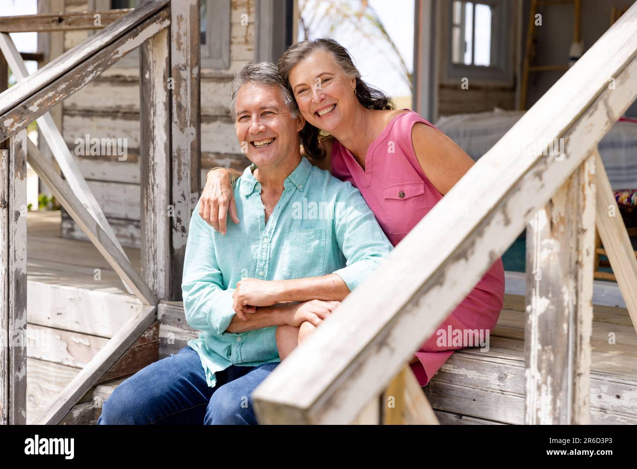 Das kaukasische Seniorenpaar lächelte fröhlich und saß auf der Treppe vor dem Cottage Stockfoto