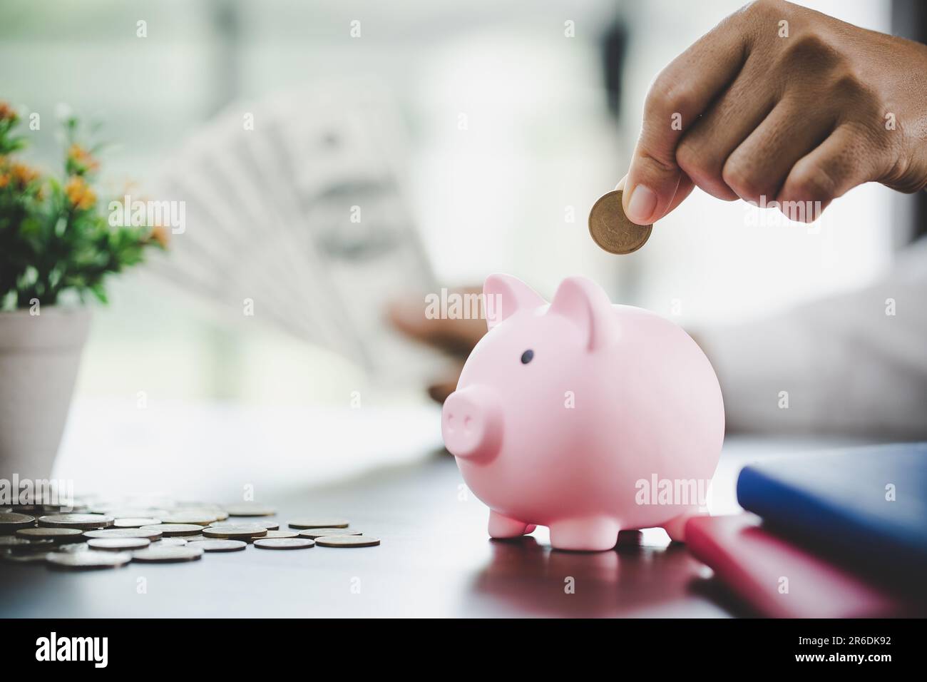 Eine Frau legt Geld ins Schweinchen, um Geld zu sparen, Vermögen und Finanzkonzept. Stockfoto