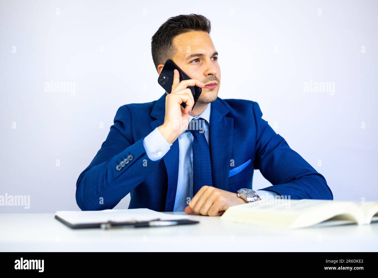Attraktiver Geschäftsmann, Wirtschaftswissenschaftler, Anwalt, Manager oder Geschäftsführer, der Finanzdokumente am Büroschreibtisch anruft und prüft. Stockfoto
