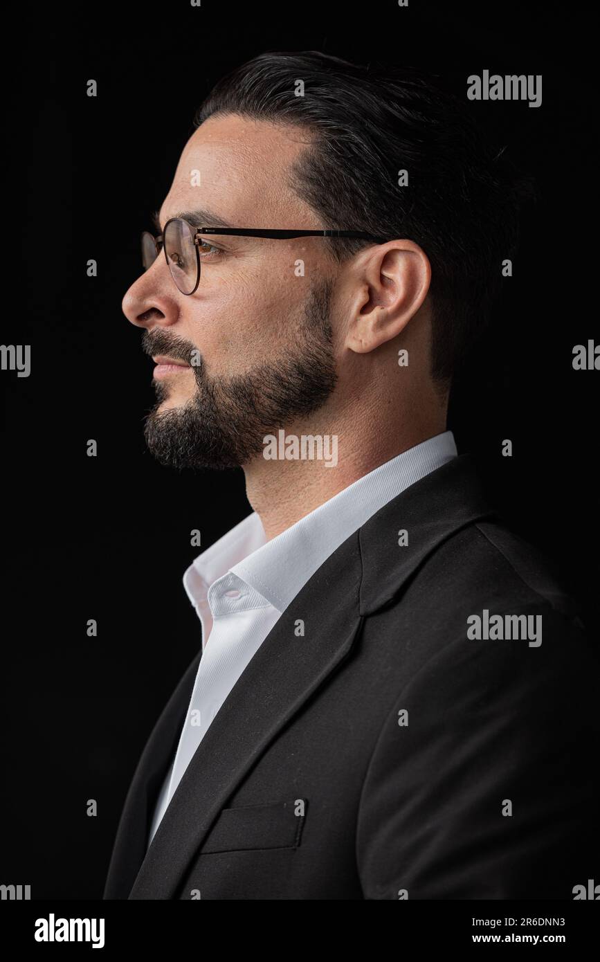 Profilansicht eines erfolgreichen Geschäftsmannes vor schwarzem Hintergrund mit Brille und Bart Stockfoto