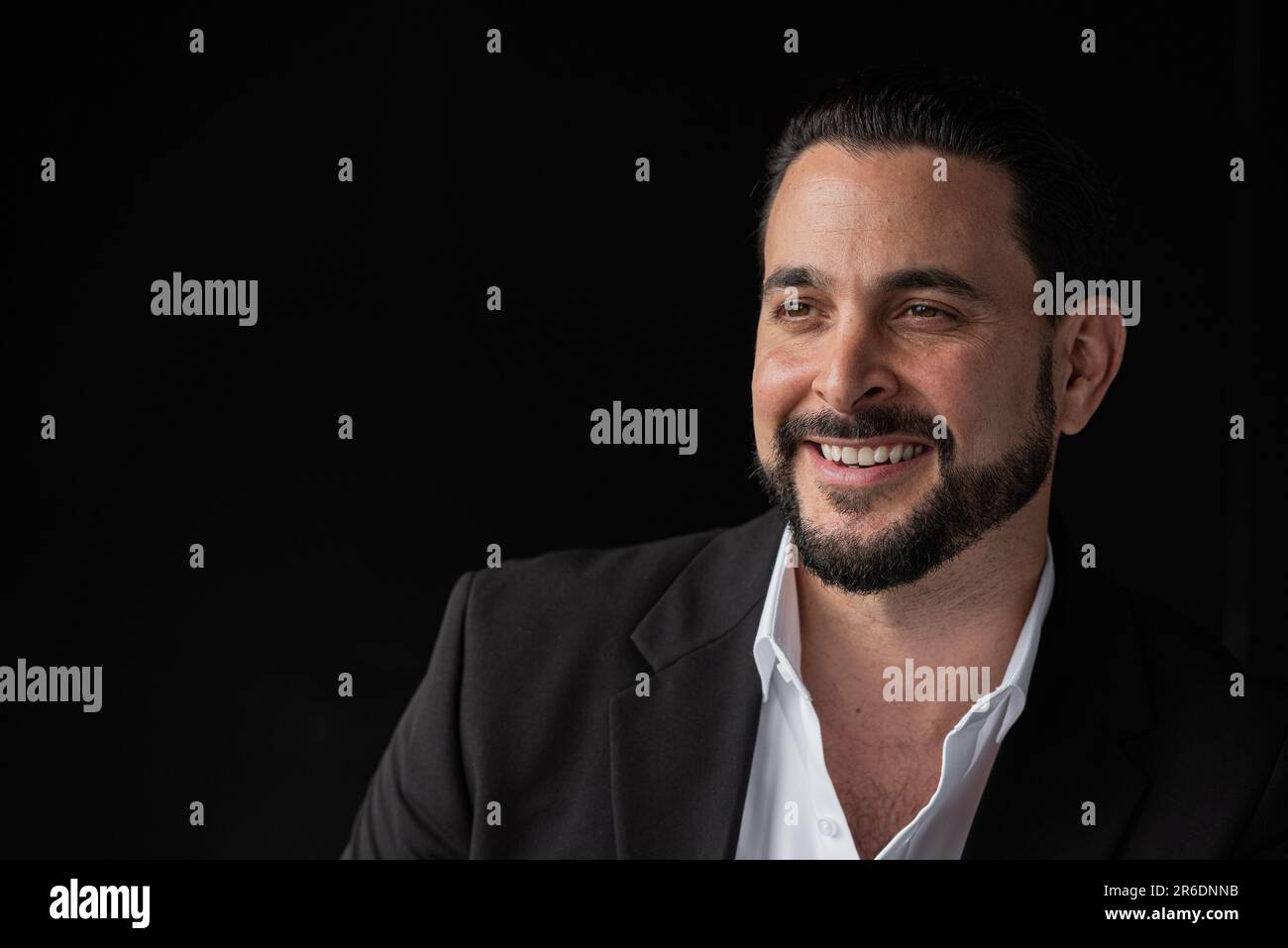 Porträt eines gutaussehenden Geschäftsmannes vor schwarzem Hintergrund und lächelndem Horizontalbild Stockfoto