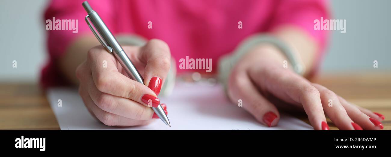 Weibliche Hände in Metallhandschellen, die erläuternde Nahaufnahme schreiben Stockfoto