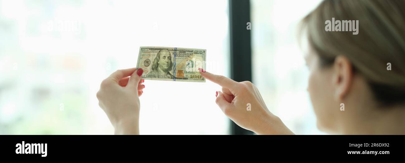 Eine Frau, die Wasserzeichen auf Geld-Dollar vor der Fensterschließung studiert Stockfoto