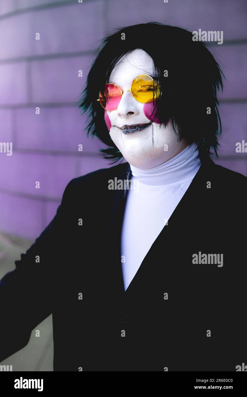 Ein glücklicher und lächelnder männlicher Cosplayer mit Gesichtsfarbe und Perücke in einem Anime-Kostüm auf einer UK Comic Con Stockfoto