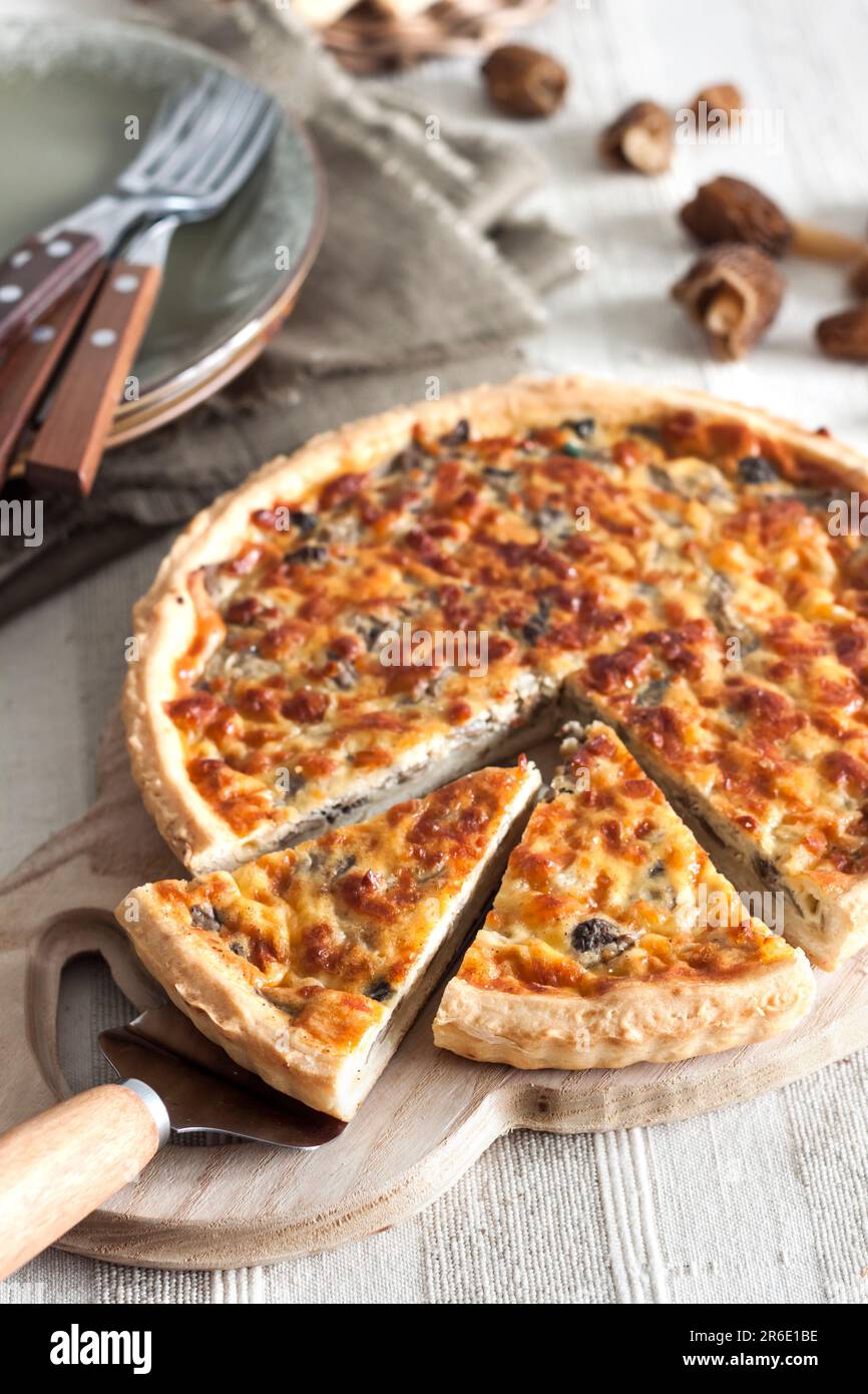 Quiche – Offene Torte mit Morchel-Pilzen, Zwiebeln und Mozzarella-Käse auf Holzbrett Stockfoto