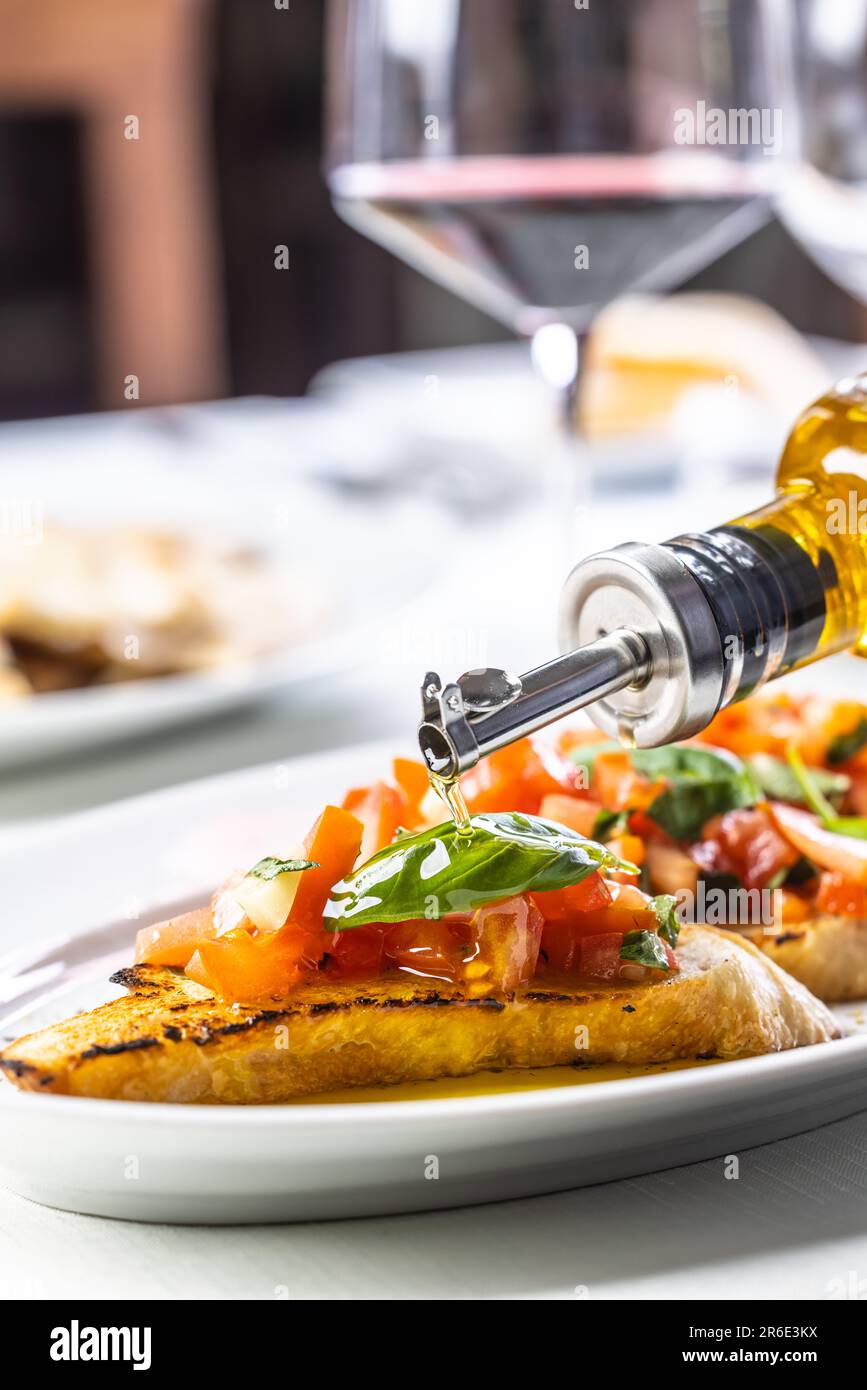 Klassisches italienisches Bruschetta mit Olivenöl und Rotweinglas im Hintergrund. Stockfoto