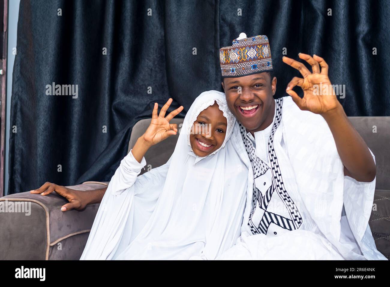 muslimischer Vater und Tochter in afrikanischer Kleidung, die Glück ausdrückt. Tochter trägt Hidschab und strahlt positive Emotionen aus Stockfoto