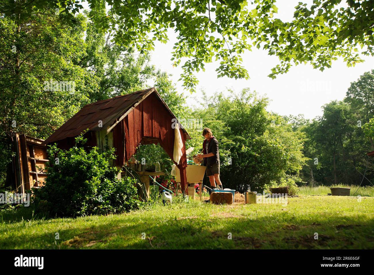 Ein Mann wäscht Geschirr auf der Farm von Circle Acres. Stockfoto
