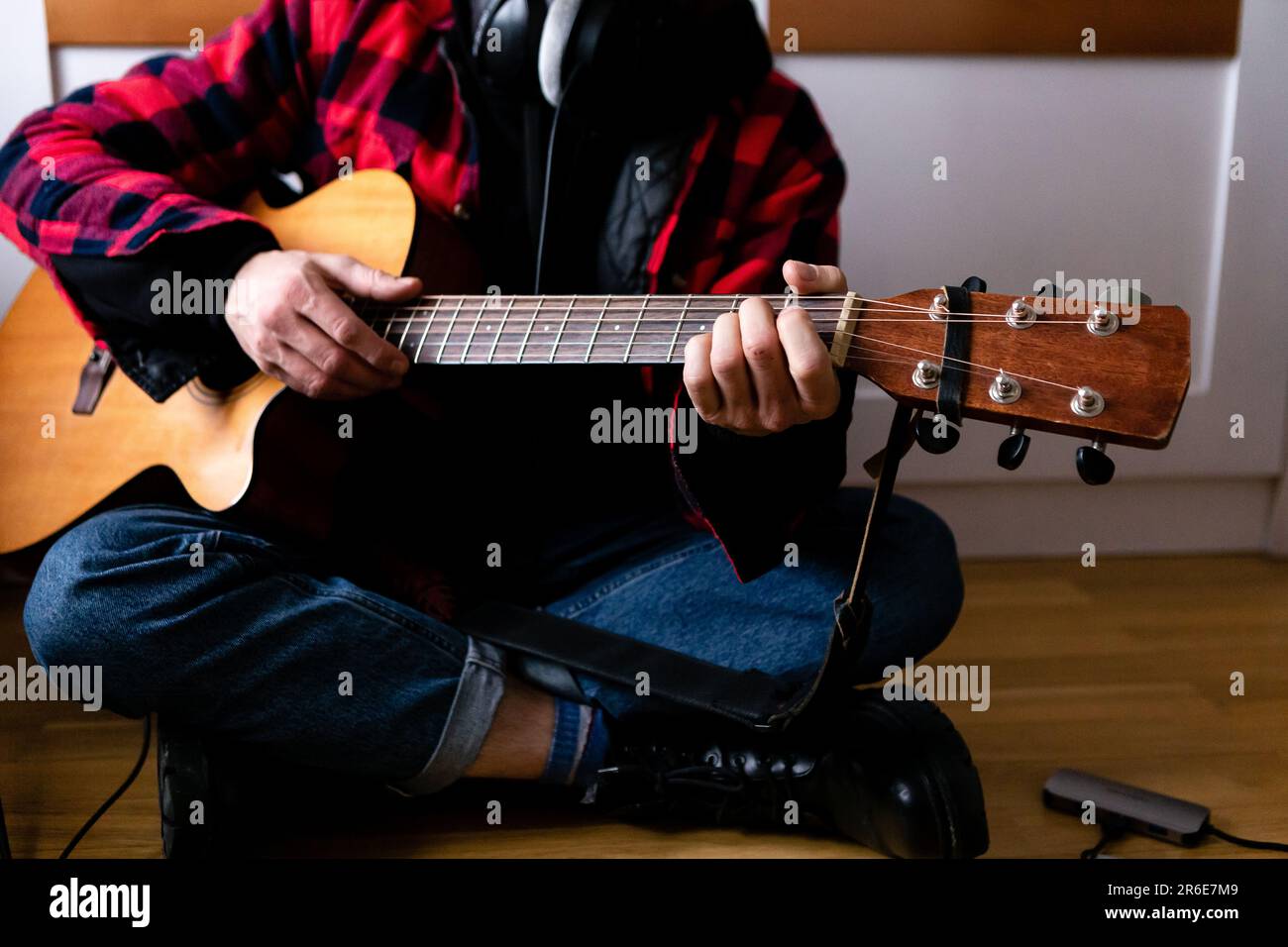 Ein Musiker in einem karierten roten Hemd spielt allein Gitarre Stockfoto
