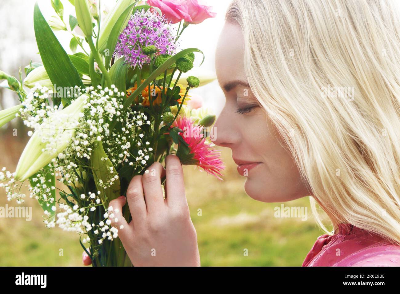 Junge blonde Frau riecht die Blumen Stockfoto