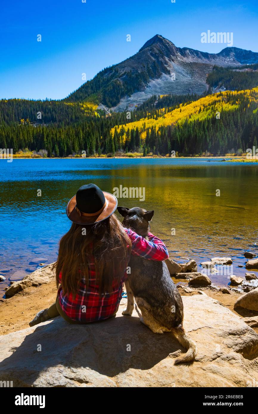 Mädchen und Hund umarmen sich im Herbst am Colorado Mountain Lake Stockfoto
