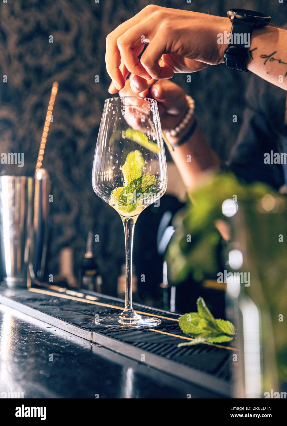 Der Barkeeper schüttete Minzblätter in Glas, er bereitet Mojito-Cocktails zu Stockfoto