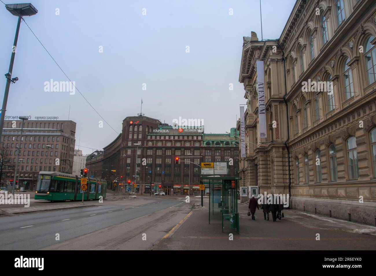 Blick auf die Innenstadt von Helsinki im Winter auf die Straße am frühen Morgen. Die HSL-Straßenbahn fährt vorbei, während Fußgänger den Fußweg entlang laufen. Helsinki, Finnland Stockfoto