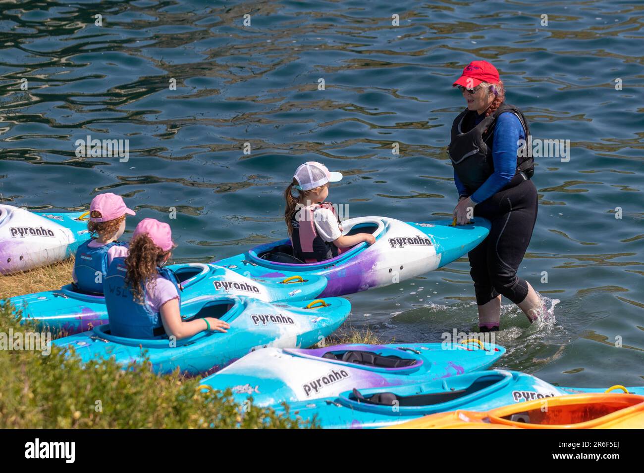 Kanufahren für Kinder in Southport, Lancashire. Juni 2023 Wetter in Großbritannien. Grundschulkinder, die eine Spritzzeit im Marine Lake haben. Anfänger überwachten den Unterricht über Wassersicherheit mit Kataka Kanu und Pyranha Kanus. Ein Katakakanu besteht aus zwei Kanus, die miteinander verbunden sind, ideal für ein geselliges Paddelerlebnis. Eine ideale Wahl für die Familie oder für diejenigen, die den See ohne das Risiko eines Kenterns erkunden möchten Stockfoto