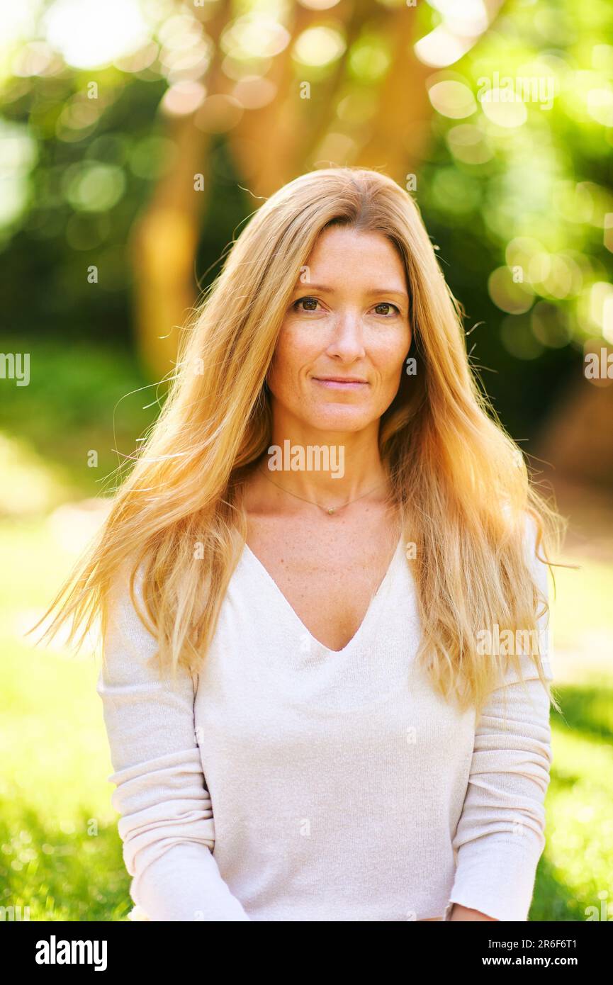 Schöne, reife Frau, die draußen in einem sonnigen Park oder Garten posiert Stockfoto