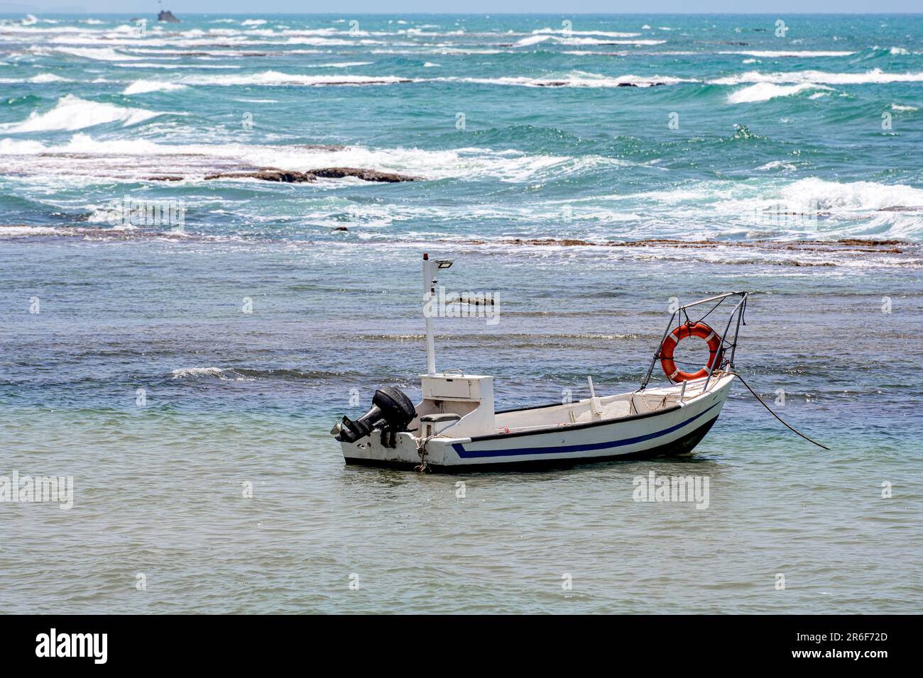 Kleines gestrandetes Fischerboot. Fotografiert in Jaffa, Israel. Bat Yam im Hintergrund Stockfoto