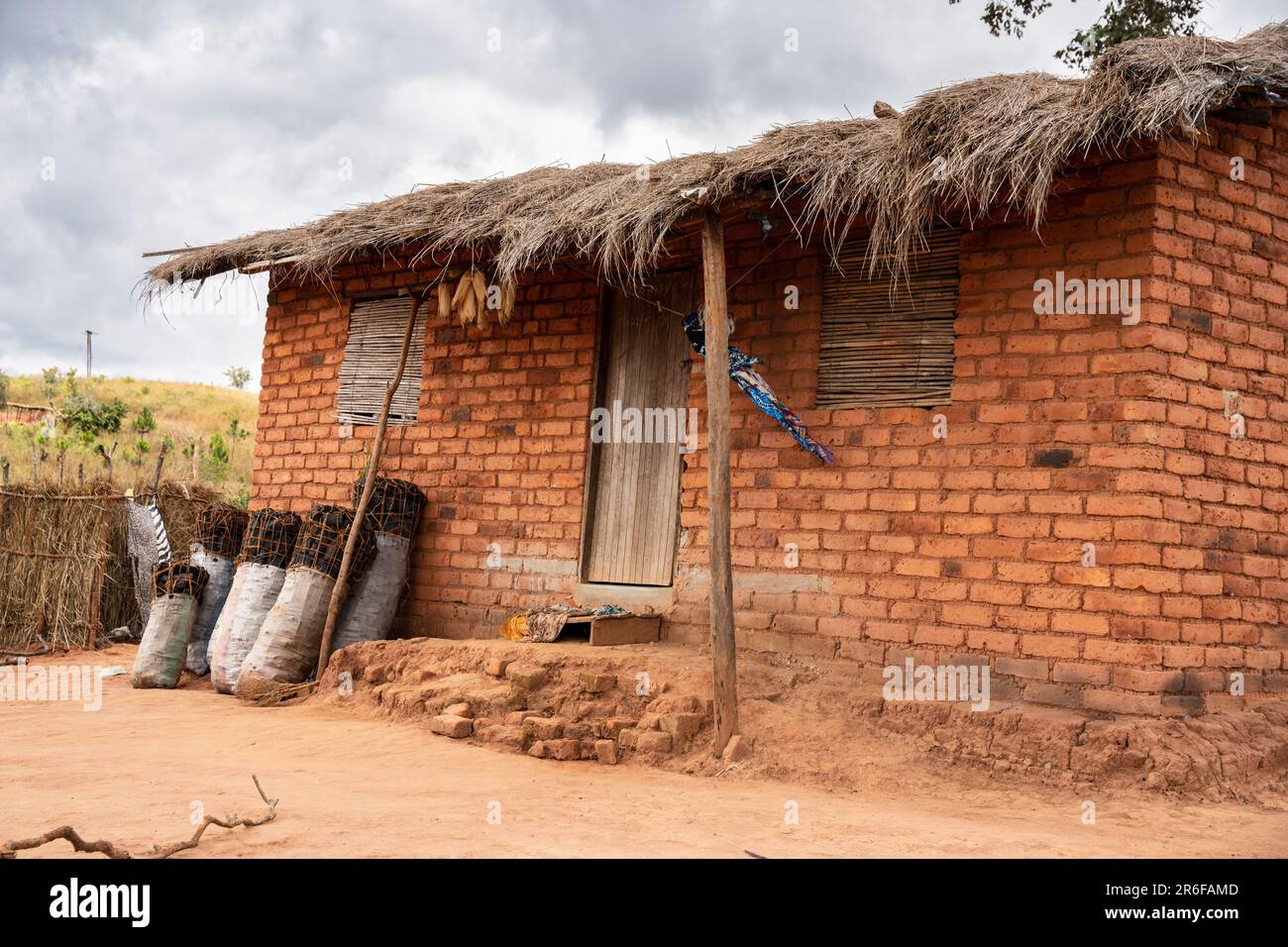 Mehrere Säcke illegal erzeugter Holzkohle werden gegen ein Haus im ländlichen Malawi gestapelt. Stockfoto
